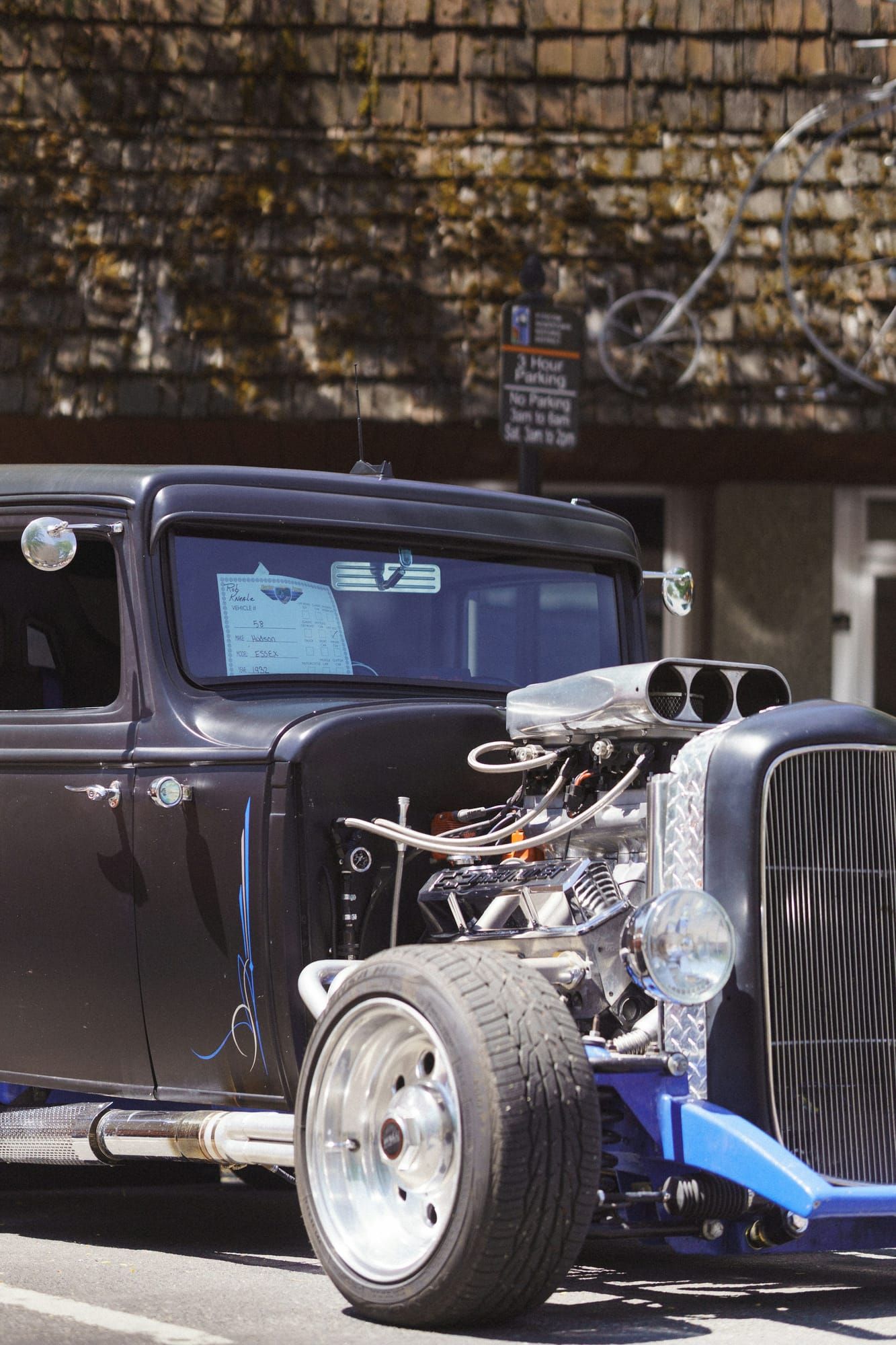 A black hot rod with a chrome engine at a car show